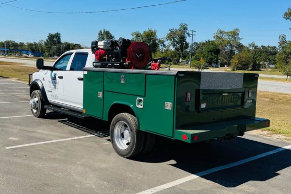 A white truck with green tool compartments facing left