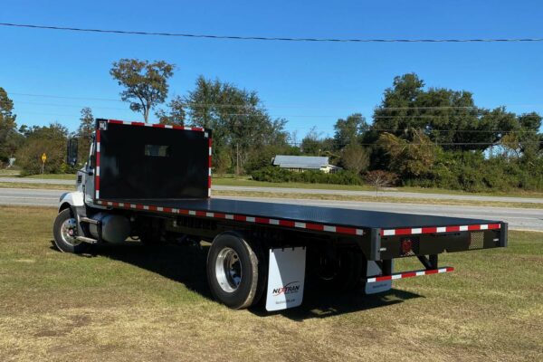 A white truck with a flatbed facing right