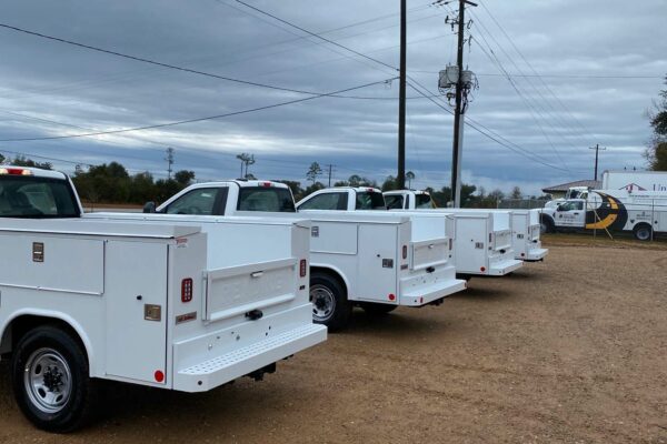 A row of white trucks with tool compartments