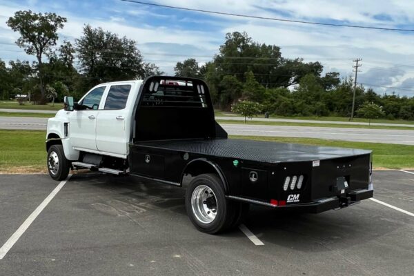 A white crew cab truck with a black flatbed viewed from left rear