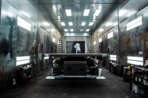 A painter applying paint to a flat bed inside the Transport Equipment Company shop