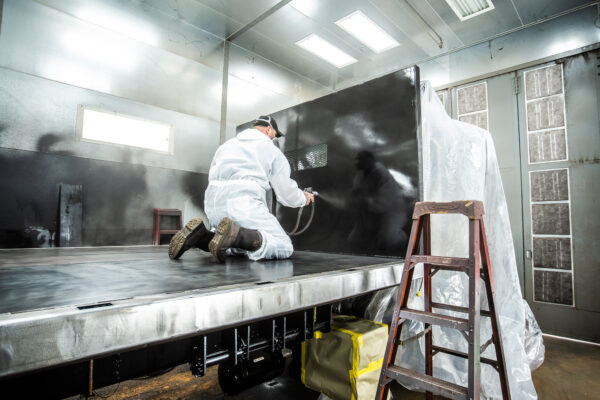 A painter applies paint to a flat bed inside the Transport Equipment Company shop