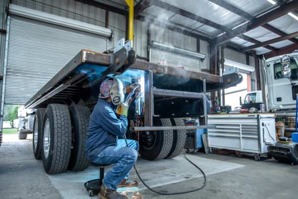 A welder welds a flatbed inside the Transport Equipment Company shop